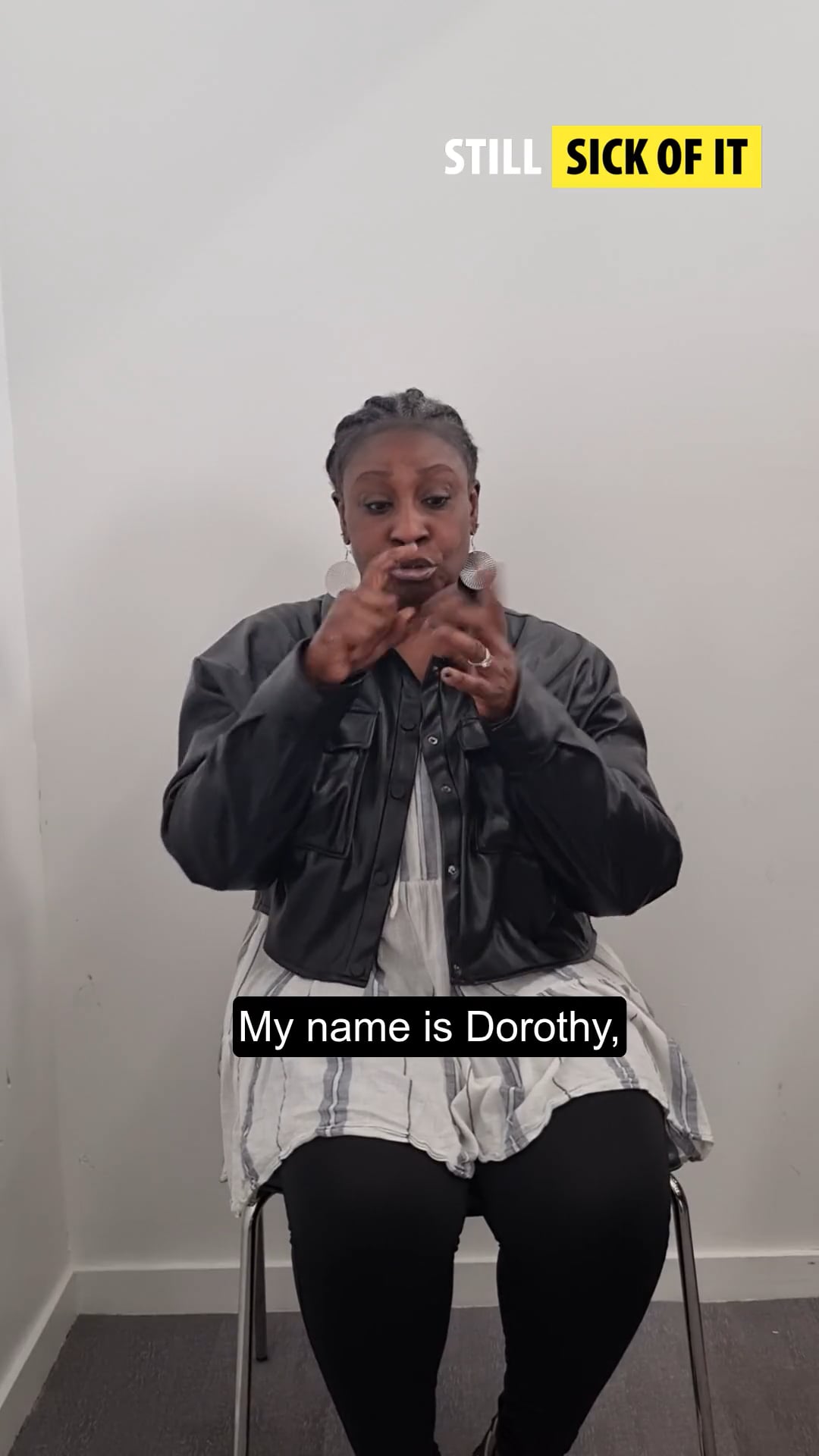 young person of colour sat down in a white top and black jacket, signing 