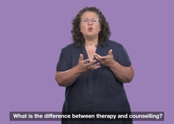 woman wearing dark shirt signing with light purple background