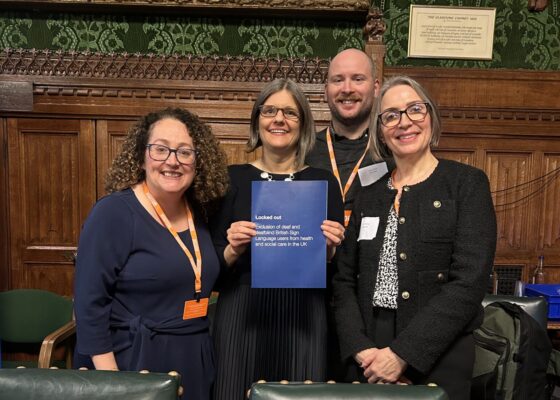 Four people standing together in parliament holding newly published report