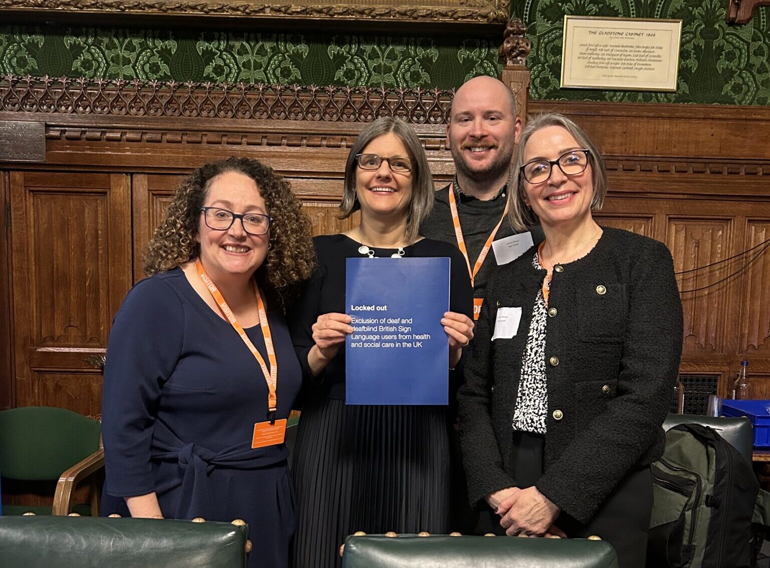 Four people standing together in parliament holding newly published report